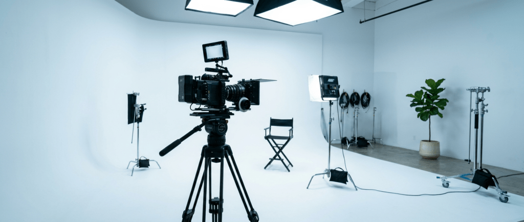Professional film camera on tripod with director's chair and studio lights